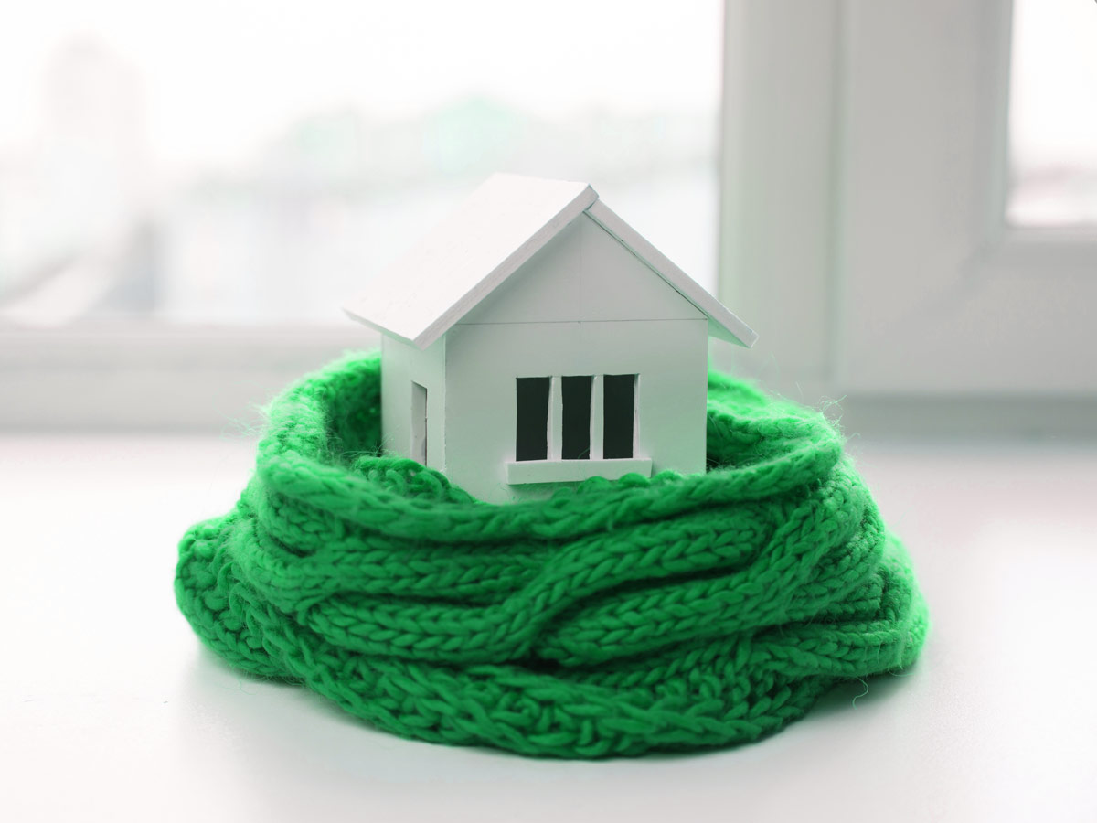 Petite maison protégée par un foulard en laine vert aux couleurs de Desjardins Assurances.